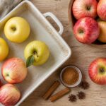 Selección de manzanas rojas, amarillas y verdes junto a utensilios de repostería